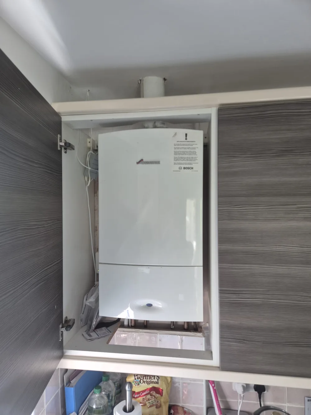 Wall-mounted domestic boiler inside a cupboard