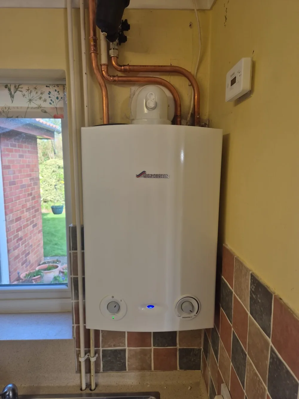 Wall-mounted boiler beside kitchen cupboards